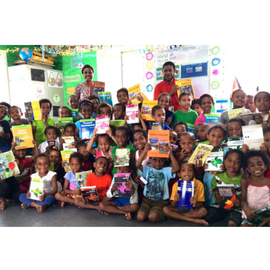 An image of smiling school kids in Papua New Guinea, holsing up their books